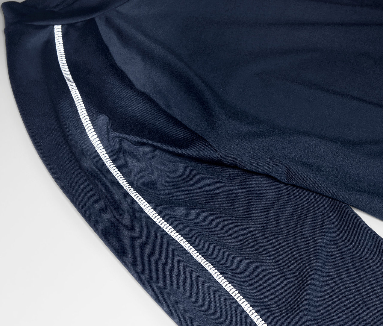 Detailaufnahme einer marineblauen Trainingshose mit einem weißen Streifen an der Seite.