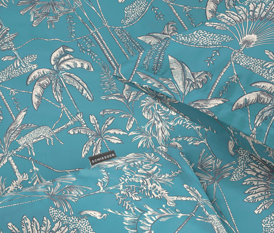 Nahaufnahme eines türkisfarbenen Stoffes mit einem weißen Dschungelmuster aus Palmen, Leoparden und Reihern.
