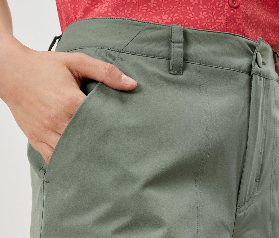 Nahaufnahme einer Person, die eine olivgrüne Hose trägt und die Hand in die Hosentasche steckt.