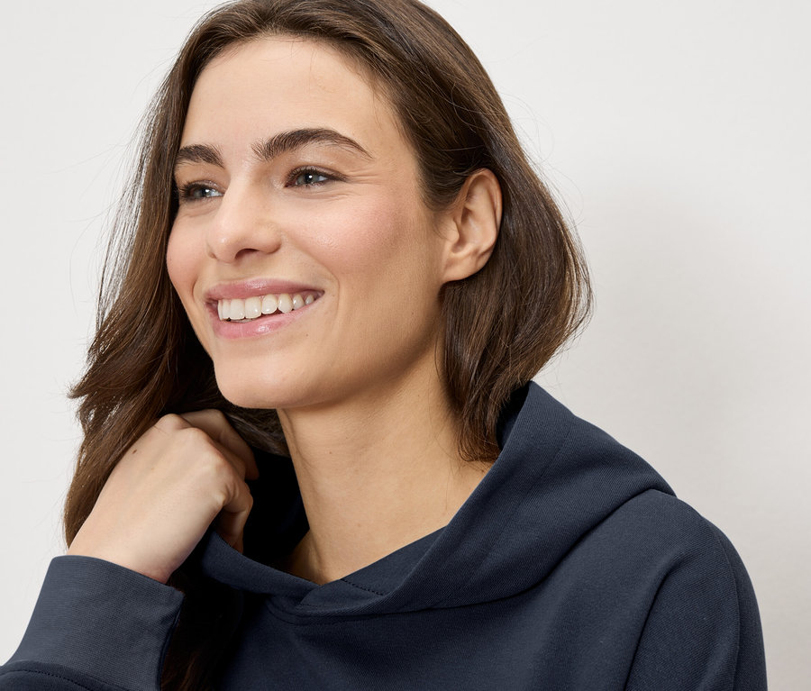 Frau lächelt und trägt einen marineblauen Hoodie.