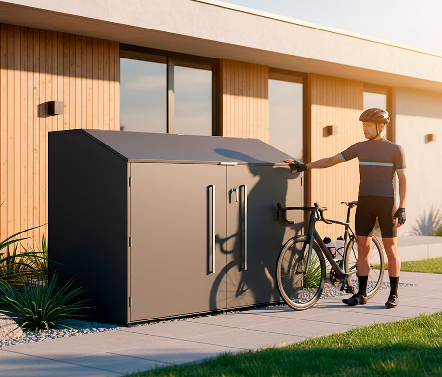Mann mit Fahrrad vor einer grauen Fahrradbox vor einem Haus.