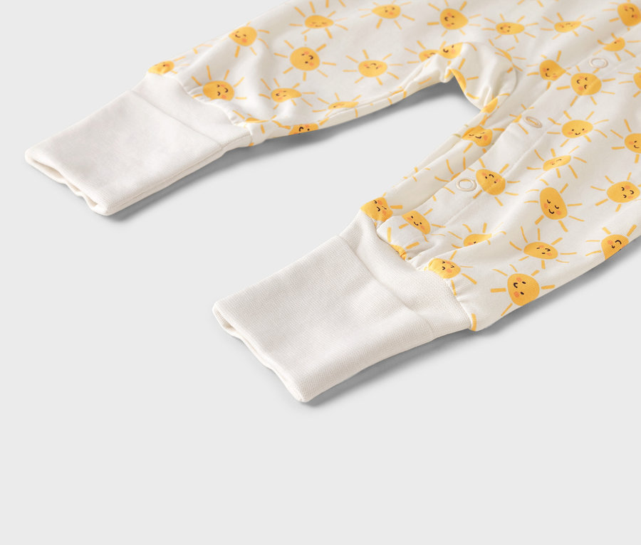 Nahaufnahme eines Baby-Stramplers mit gelbem Sonnenmuster und weißen Bündchen.
