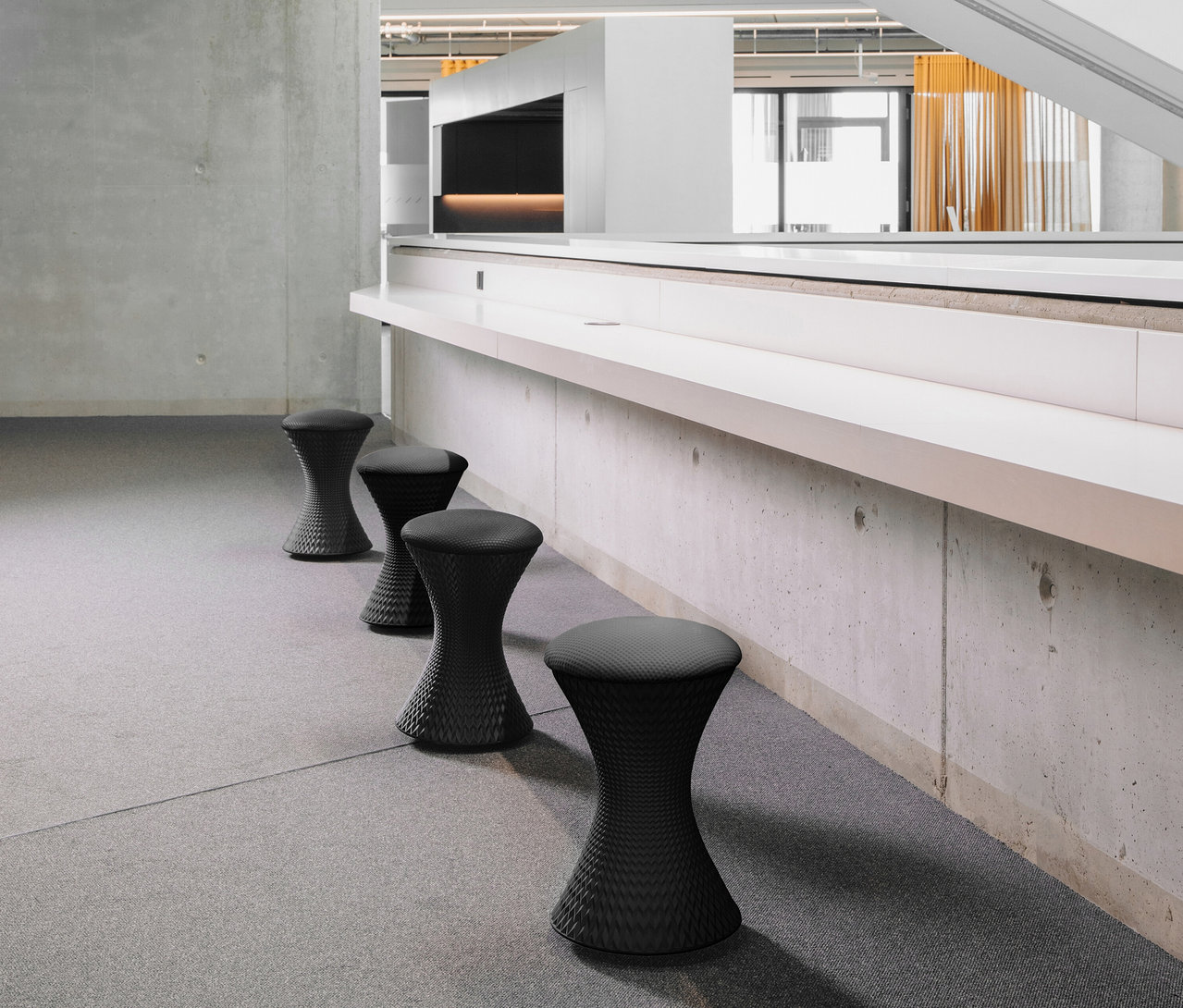 Vier schwarze Sitness »3D Stool« Hocker stehen in einer Reihe vor einer Wand.
