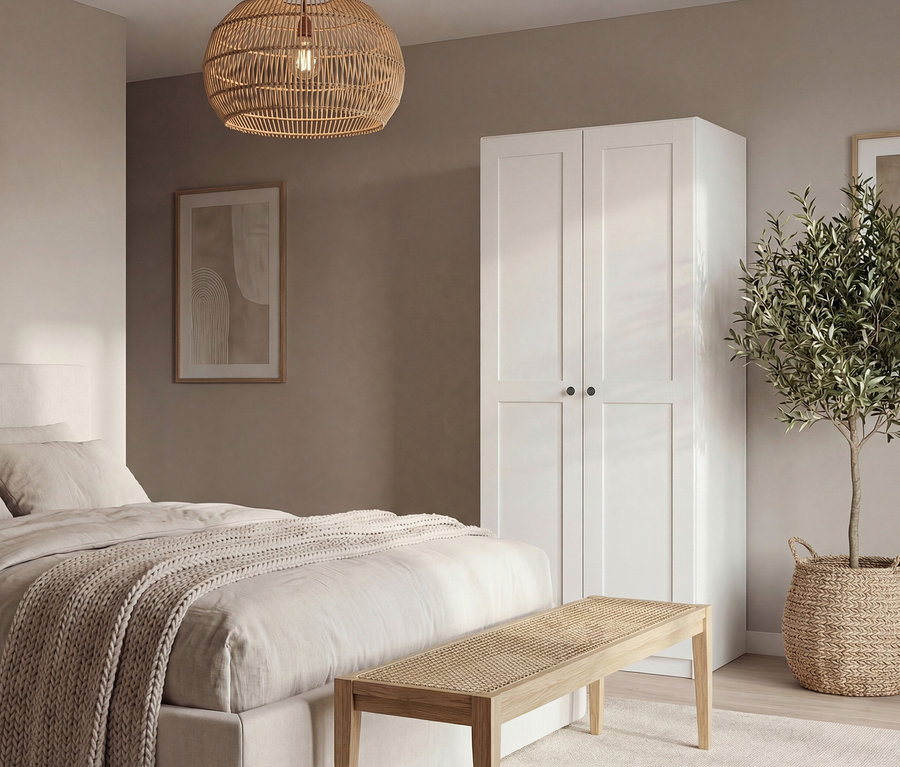Schlafzimmer mit Doppelbett, weißem Schrank, Bank und Topfpflanze. Über dem Bett hängt eine geflochtene Lampe.