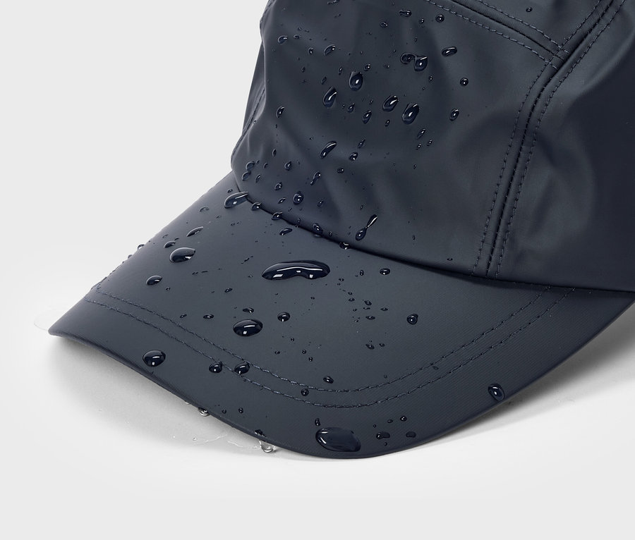 Nahaufnahme einer marineblauen Baseballkappe mit Wassertropfen auf dem Schirm und der Oberseite.