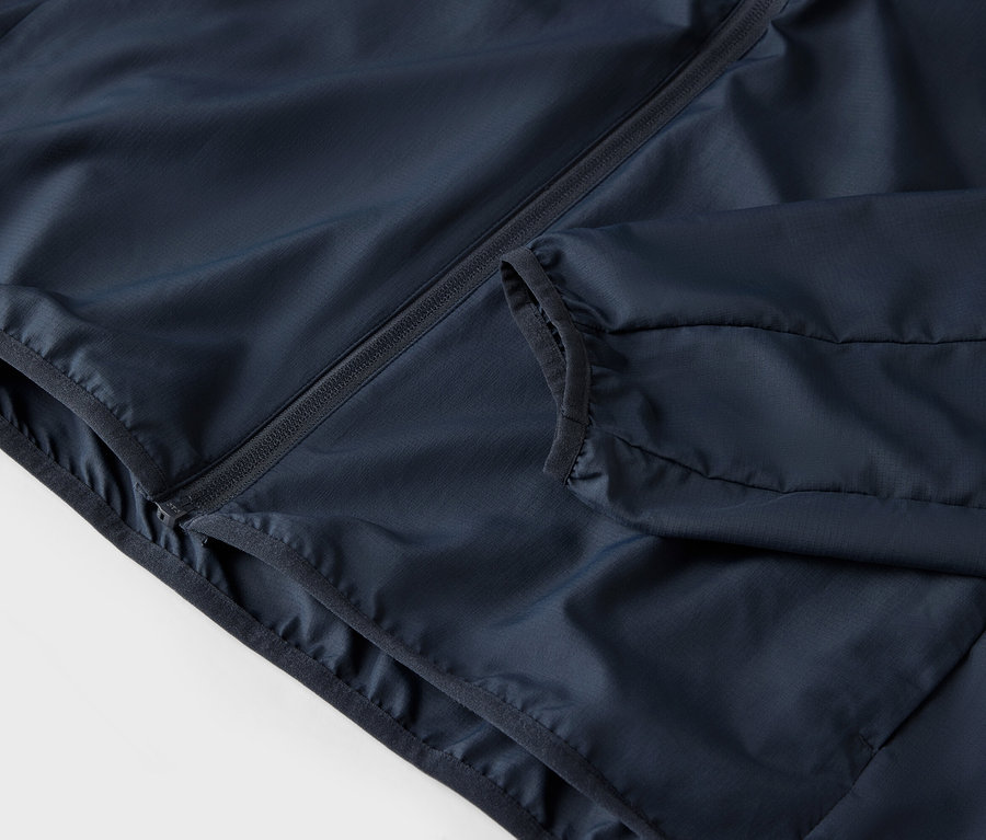 Detailaufnahme einer marineblauen Jacke mit Reißverschluss und Taschen.