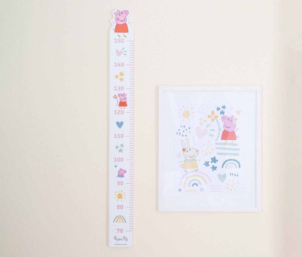 An einer hellbeigen Wand hängen ein Peppa Pig-Wachstumsdiagramm und ein gerahmtes Bild.