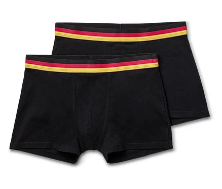 Zwei schwarze Boxershorts liegen übereinander, mit einem rot-goldenen Bund.
