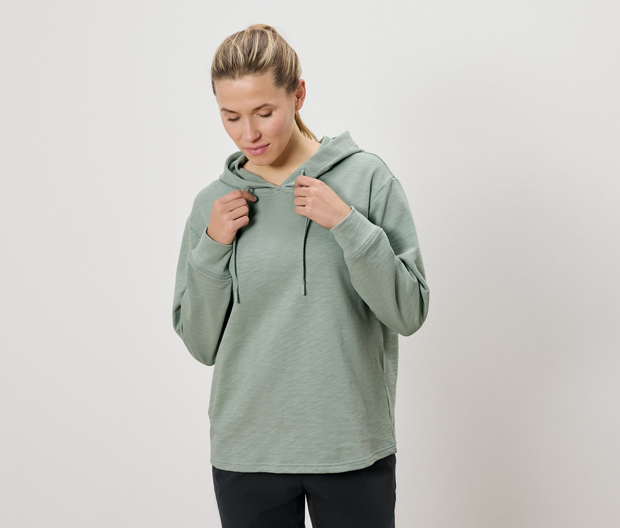 Frau hält die Kordel einer mintgrünen Kapuzenjacke.