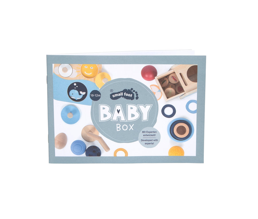 Verpackung der "Baby Box" mit Abbildungen von Holzspielzeug, darunter ein Wal, Ringe und ein Steckspiel.