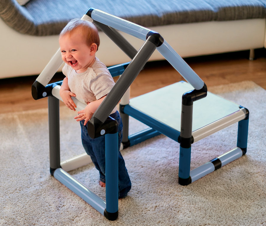 Lachendes Kind steht an blau-grauem Quadro-Home-BEGINNER-Set.