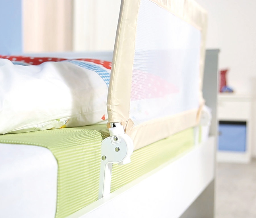 Detailansicht eines beigen roba Bettschutzgitters »Klipp-Klapp«, das an einem weißen Bett befestigt ist.