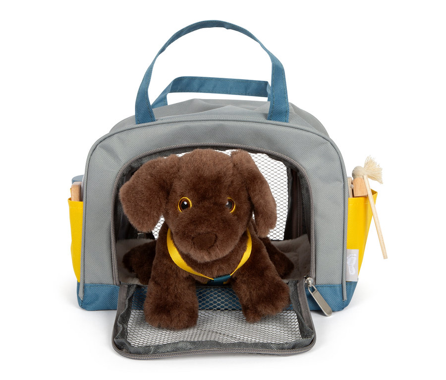 Ein brauner Plüschhund sitzt in einer grauen Tasche mit blauen Griffen und gelben Taschen, es handelt sich um ein "small foot Hund mit Tasche und Pflege-Set".