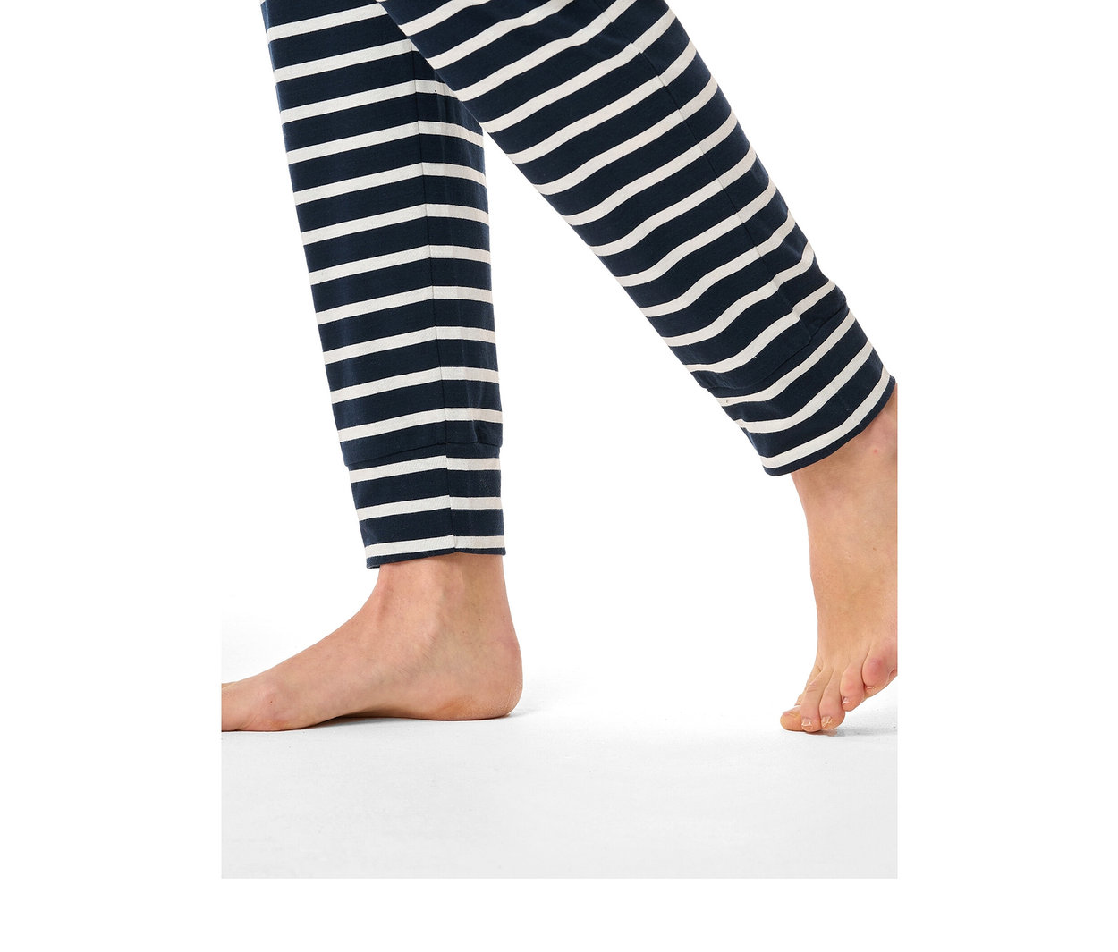 Beine und Füße einer Person in dunkelblau-weiß gestreiften SCHIESSER Pyjama-Hosen, ein Fuß flach, der andere auf Zehenspitzen.