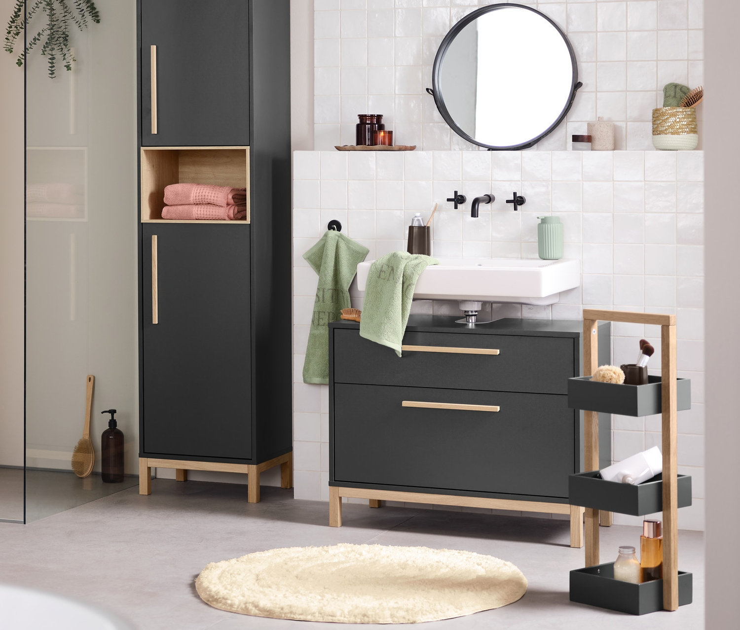 Badezimmer Interieur mit Waschbecken, Spiegel und Eklund Badschränken in Anthrazit. Im Vordergrund befindet sich eine Badewanne.