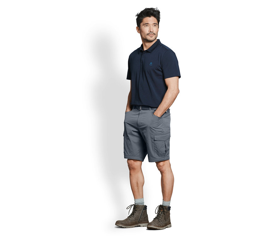 Mann posiert in marineblauem Poloshirt und grauer 2-in-1-Funktionshose.