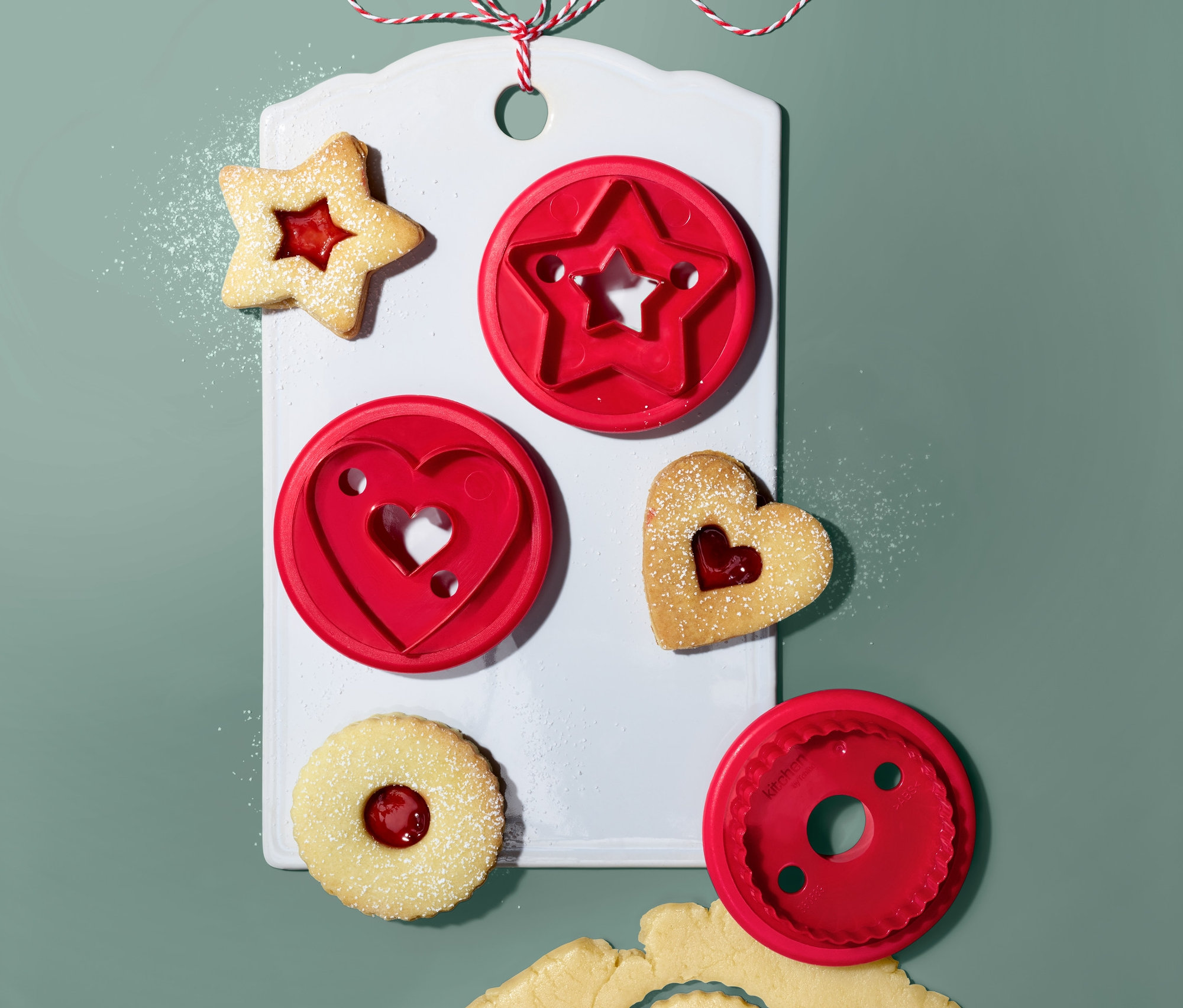 Linzer-Plätzchen-Ausstecher (3 Stk.) auf einem weißen Brett mit Stern-, Herz- und Kreisform. Ausgestochene Formen mit Marmelade und Teig.