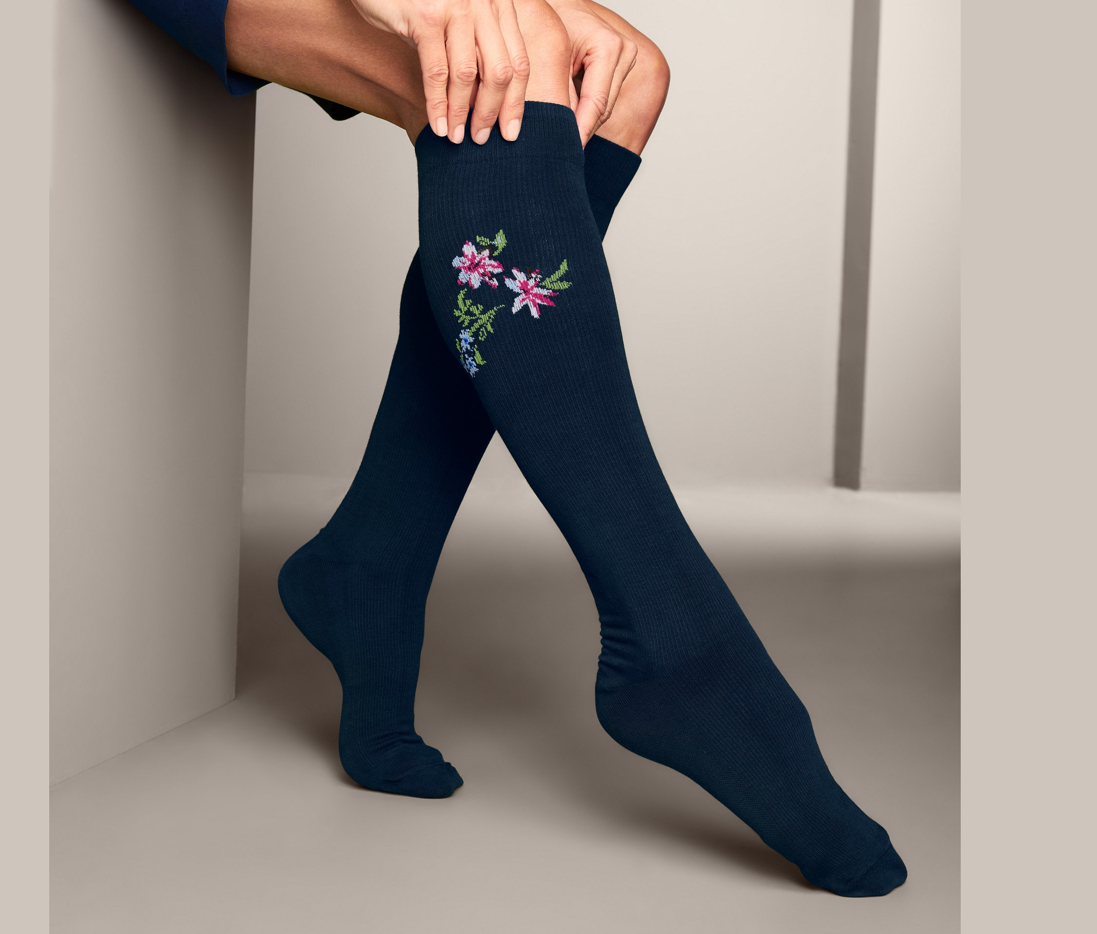 Frau richtet blaue 2 Paar Stützkniestrümpfe mit Blumenmuster.