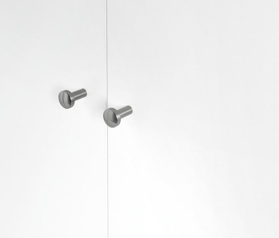 Detailaufnahme eines weißen Schranks mit Furnierkanten und zwei runden Metallgriffen.
