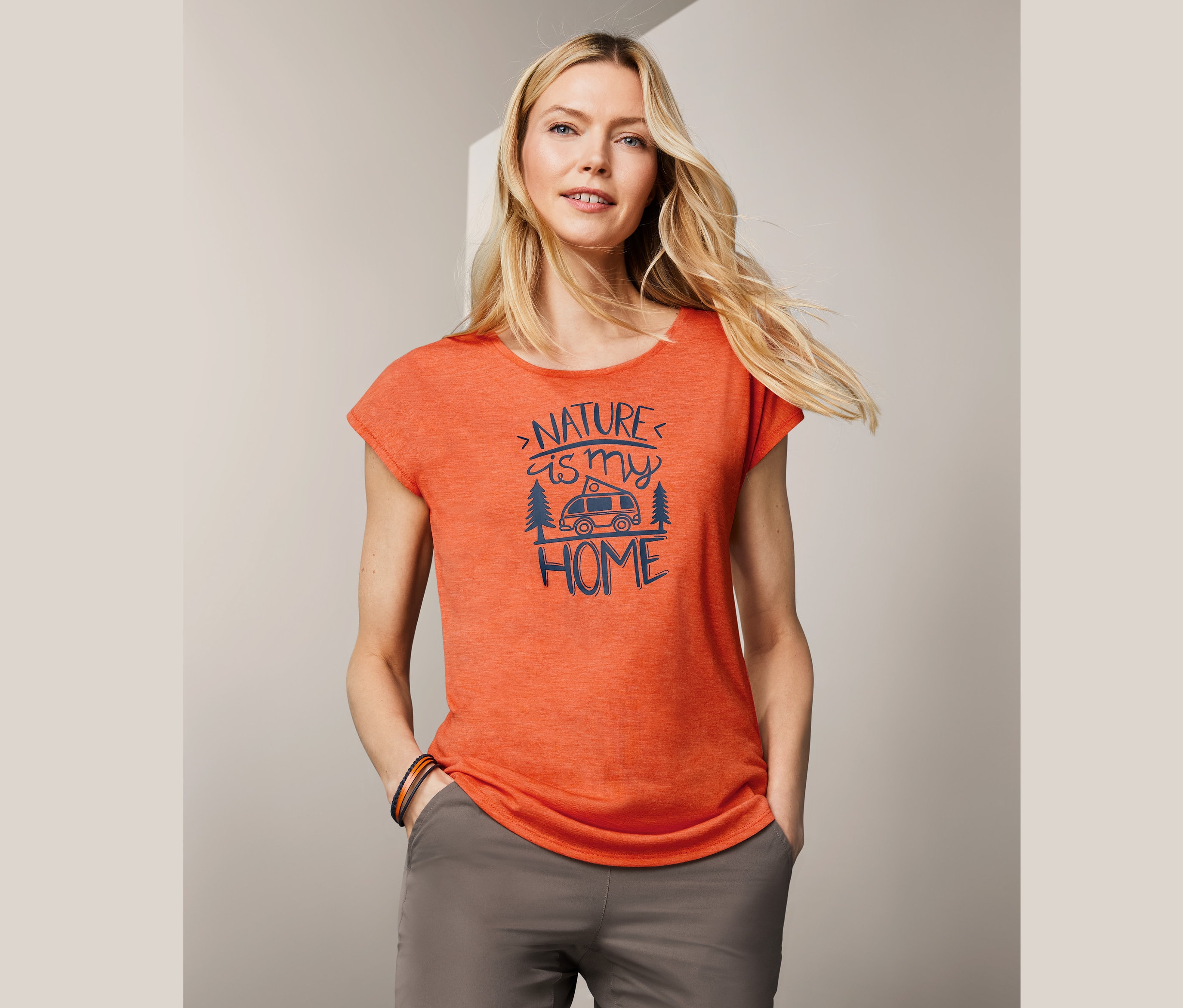 Blonde Frau trägt ein orangefarbenes Funktionsshirt mit Aufdruck.