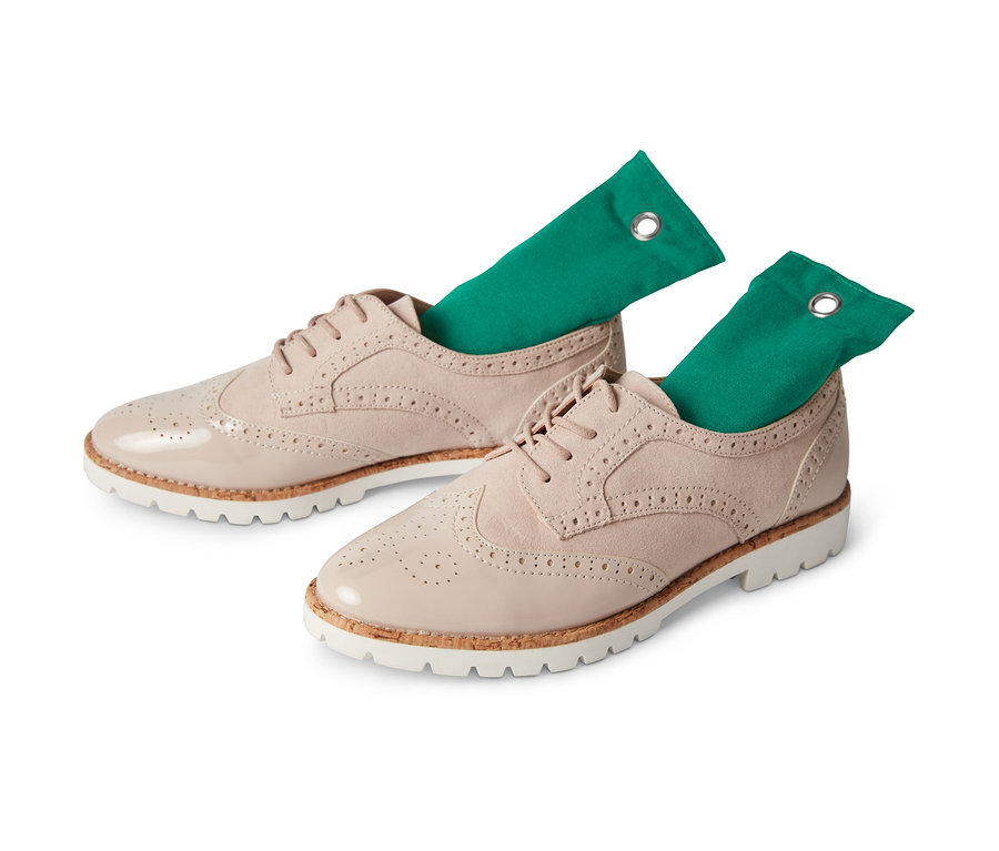 Zwei beige Schnürschuhe, in denen jeweils ein grüner 2 Schuh-Geruchsentferner steckt.