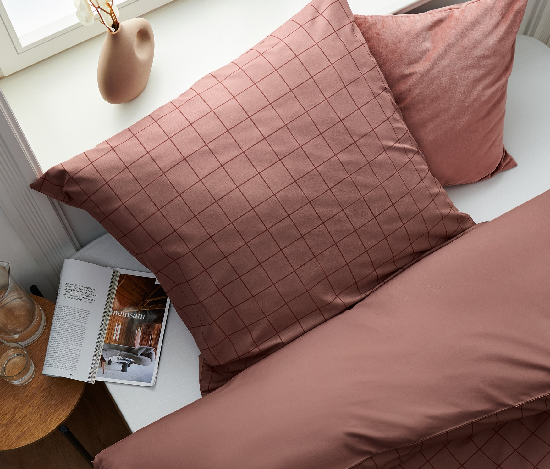 Detailansicht von oben eines Bettes mit karierter Bettwäsche und Kissen.