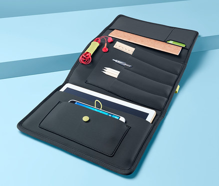 Geöffnete Büroutensilien-Mappe mit Fächern für Tablet, Handy, Kopfhörer, Stifte und Lineal auf blauem Hintergrund.