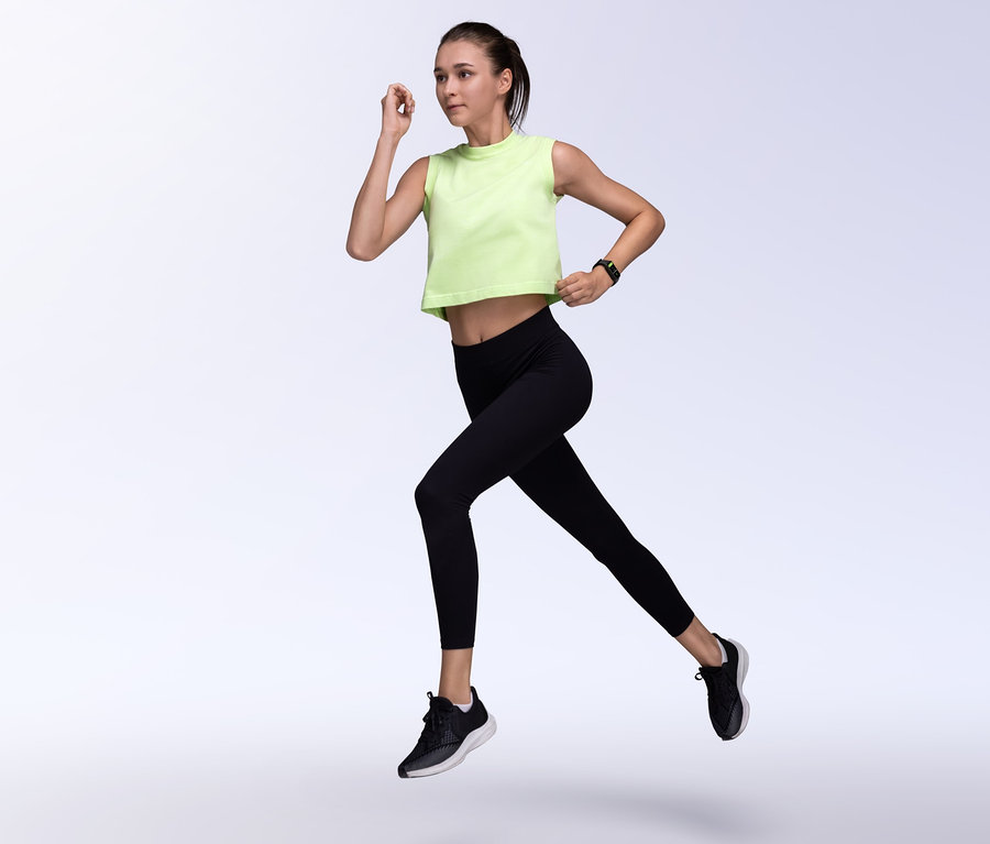 Frau in grünem Top und schwarzen Leggings rennt, sie trägt einen schwarzen Amazfit Band 7 Aktivitätstracker, schwarz.
