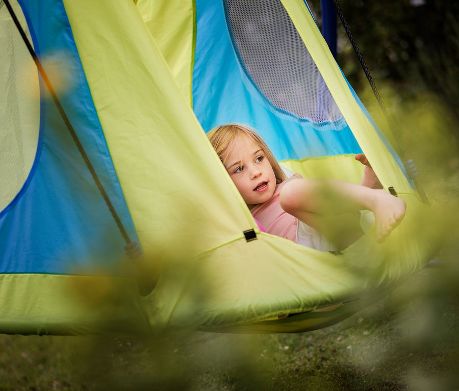 Mädchen liegt im HUDORA Nestschaukel-Zelt Cosy Castle 110.
