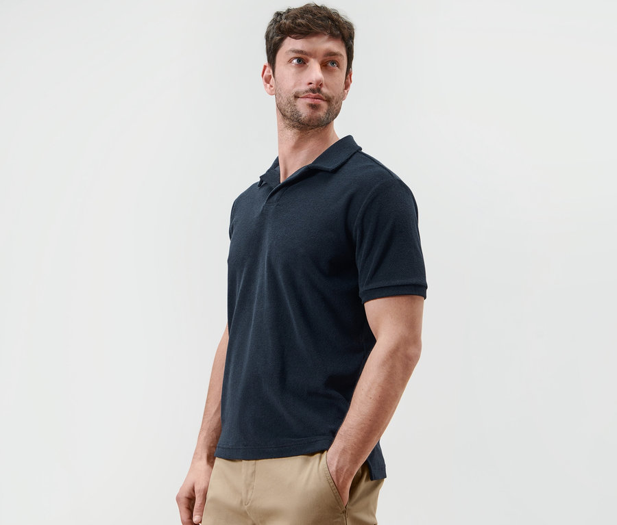 Mann posiert in marineblauem Frottee-Poloshirt.