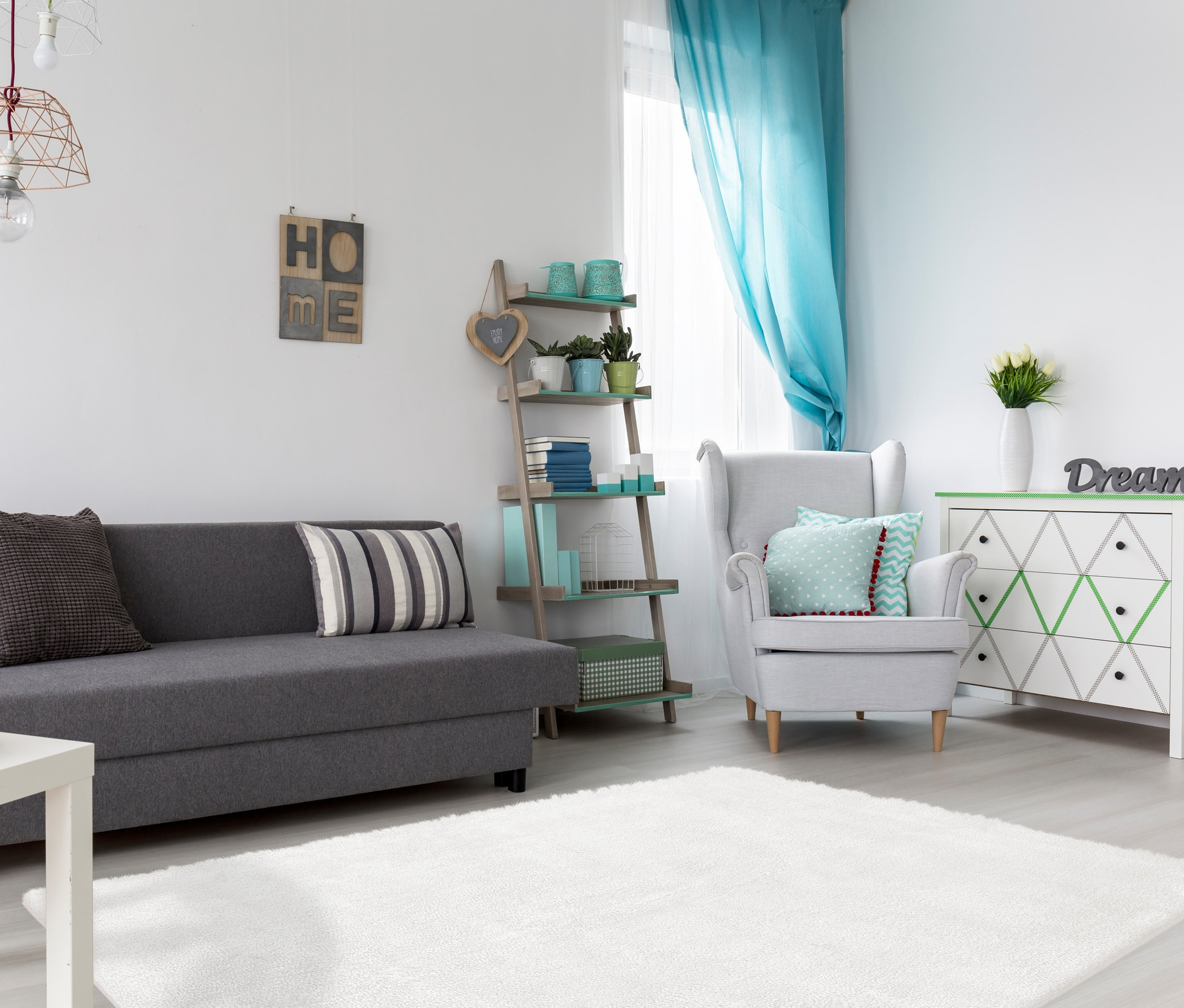 Wohnzimmer mit grauem Sofa, weißem Teppich und Dekorationen.