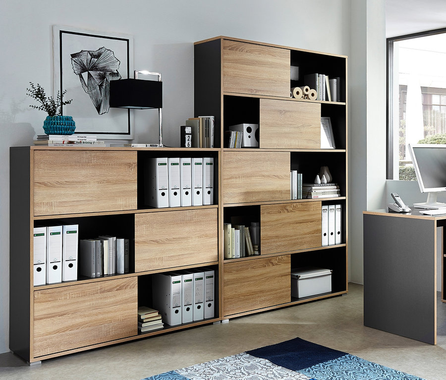 Innenaufnahme mit großem Schiebetürregal »Slide« in Anthrazit/Eiche-Nachbildung und Eckschreibtisch »Slide« in Anthrazit/Eiche.