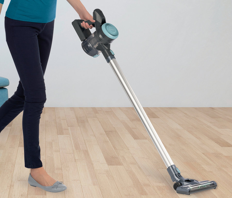 Frau saugt den Boden mit einem Akku-Hand- und Bodenstaubsauger.