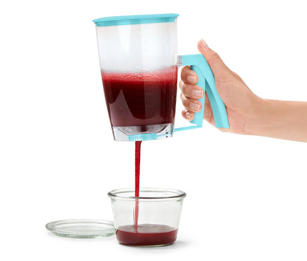 Eine Frau gießt Teig aus einem Teigportionierer in ein Glas.