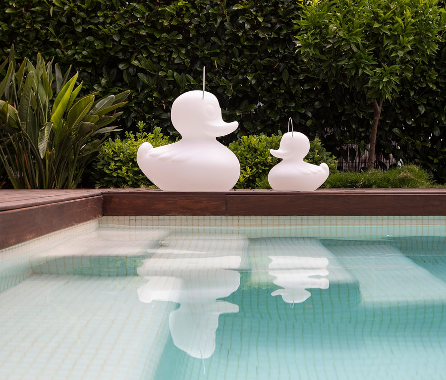 Zwei weiße Goodnight Light LED-Leuchten »Ente« stehen am Pool.