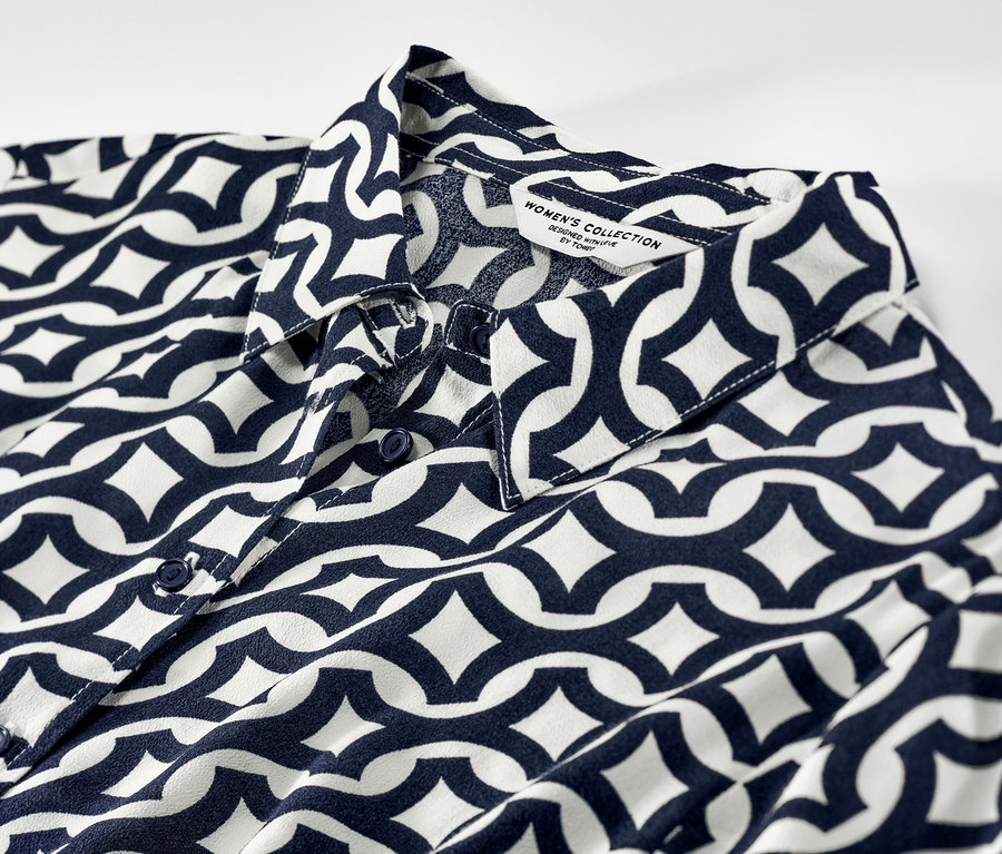 Detailansicht eines bedruckten Hemdblusenkleids mit blau-weißem geometrischem Muster.