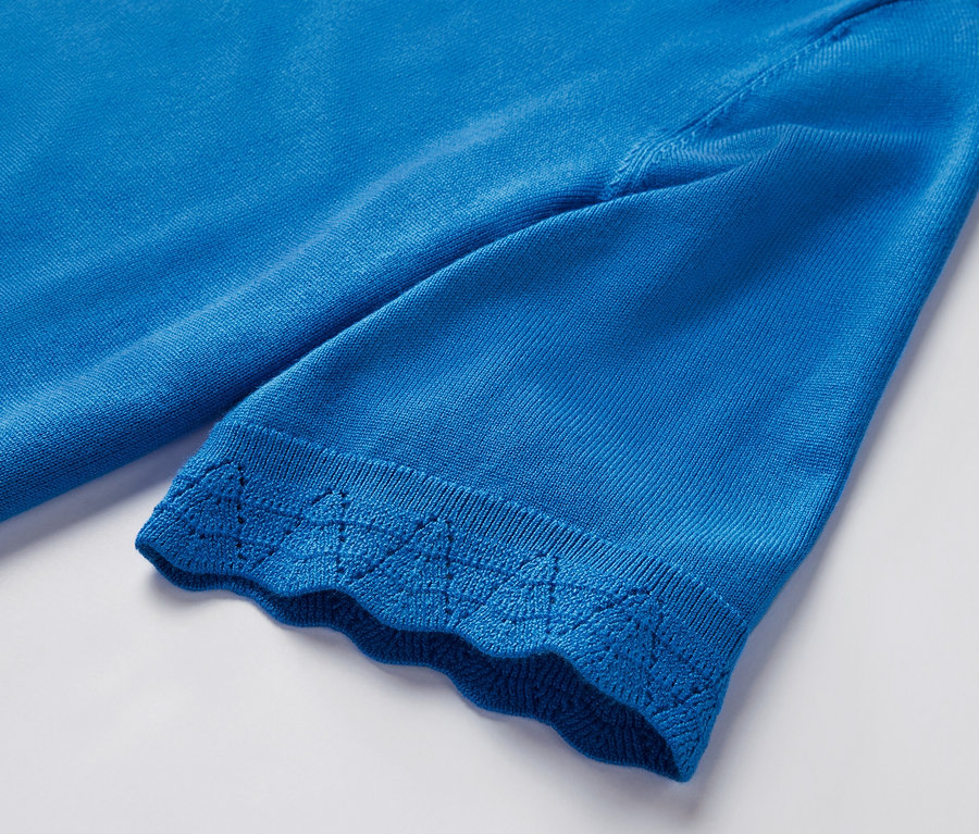 Detailansicht eines kobaltblauen Feinstrickpullovers mit kurzem Ärmel und Zierrand.