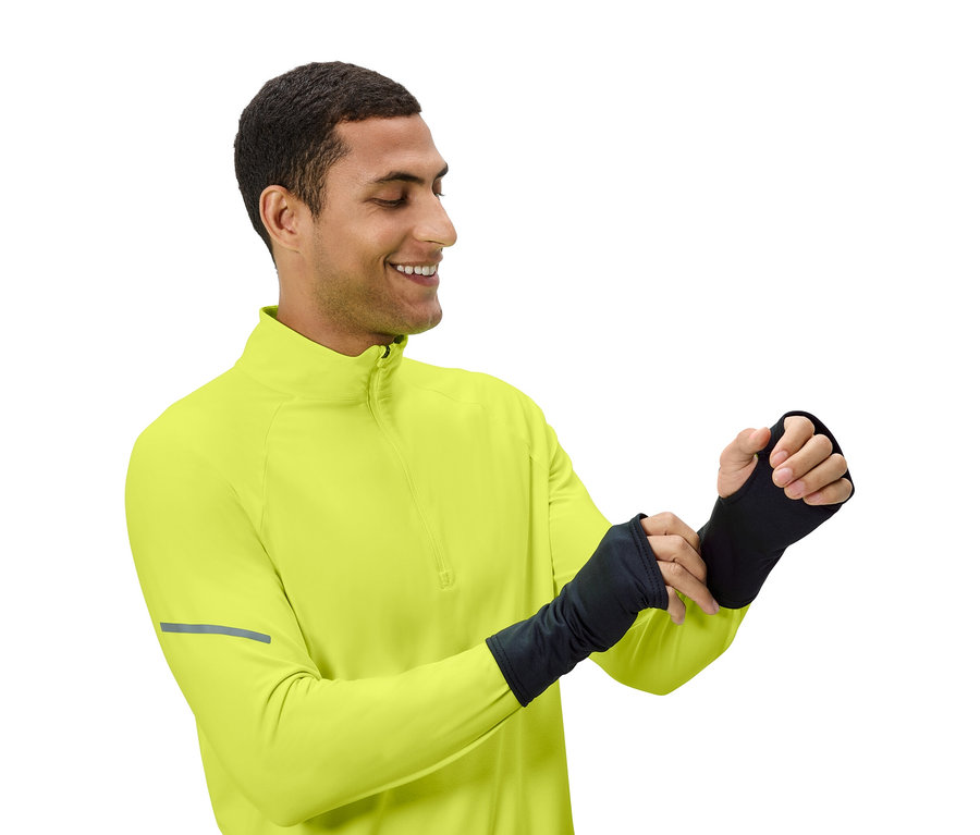 Mann justiert schwarze Armstulpen, trägt ein gelbgrünes Oberteil.