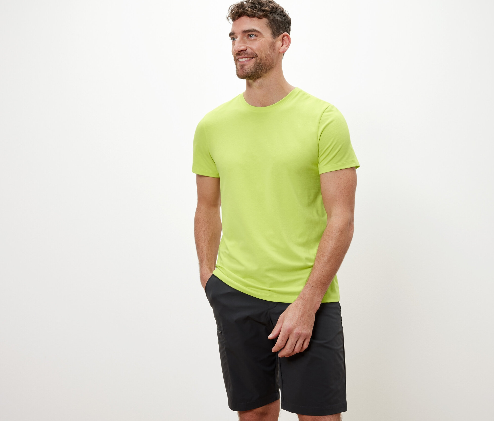 Mann mit braunen Haaren posiert vor weissem Hintergrund in einem limefarbenen Funktionsshirt.