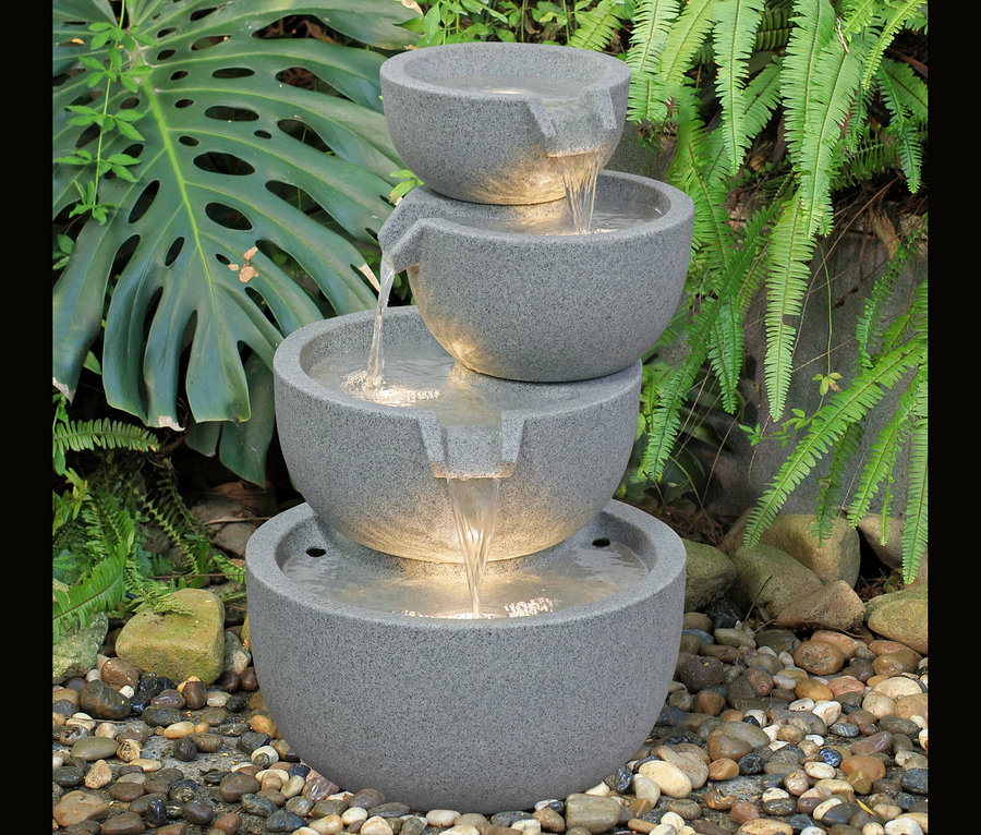 4-stufiger LED-Gartenbrunnen »Rama« mit fließendem Wasser, umgeben von Grün.