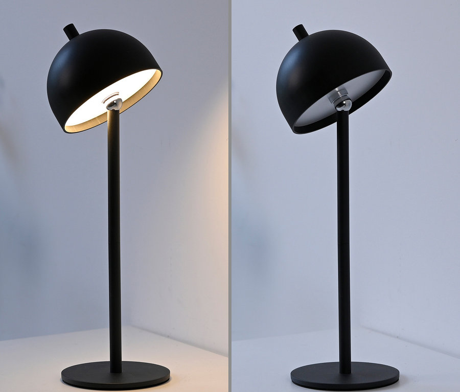 Zwei schwarze Lampen stehen auf einem Tisch, eine leuchtet, die andere nicht.