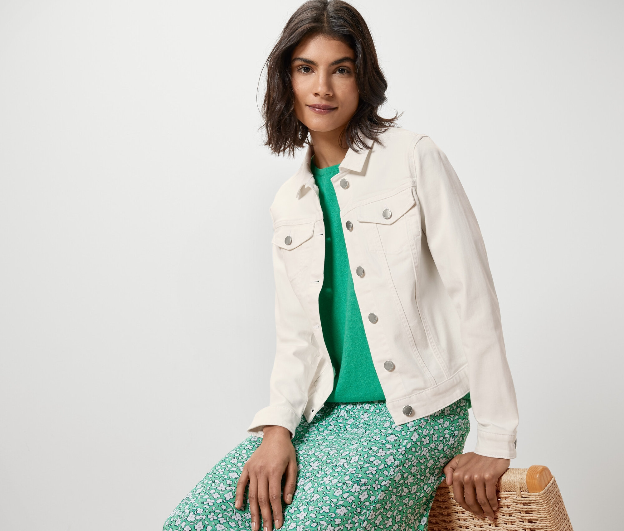 Frau sitzt und trägt eine Jeansjacke.