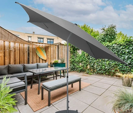 Grauer Leco Marktschirm 250 x 250 cm mit Bezug steht über einem grauen Sofa, Tisch und Bank auf einer Terrasse.