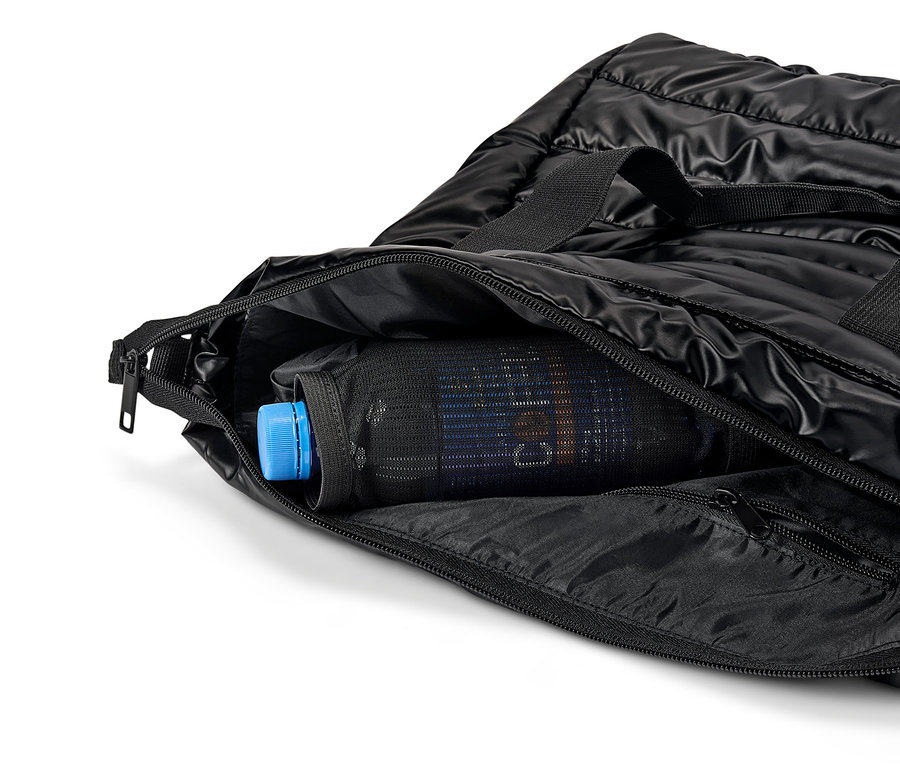 Schwarze Stepptasche mit offenem Reißverschluss und einer Flasche mit blauem Verschluss in einer Netztasche.