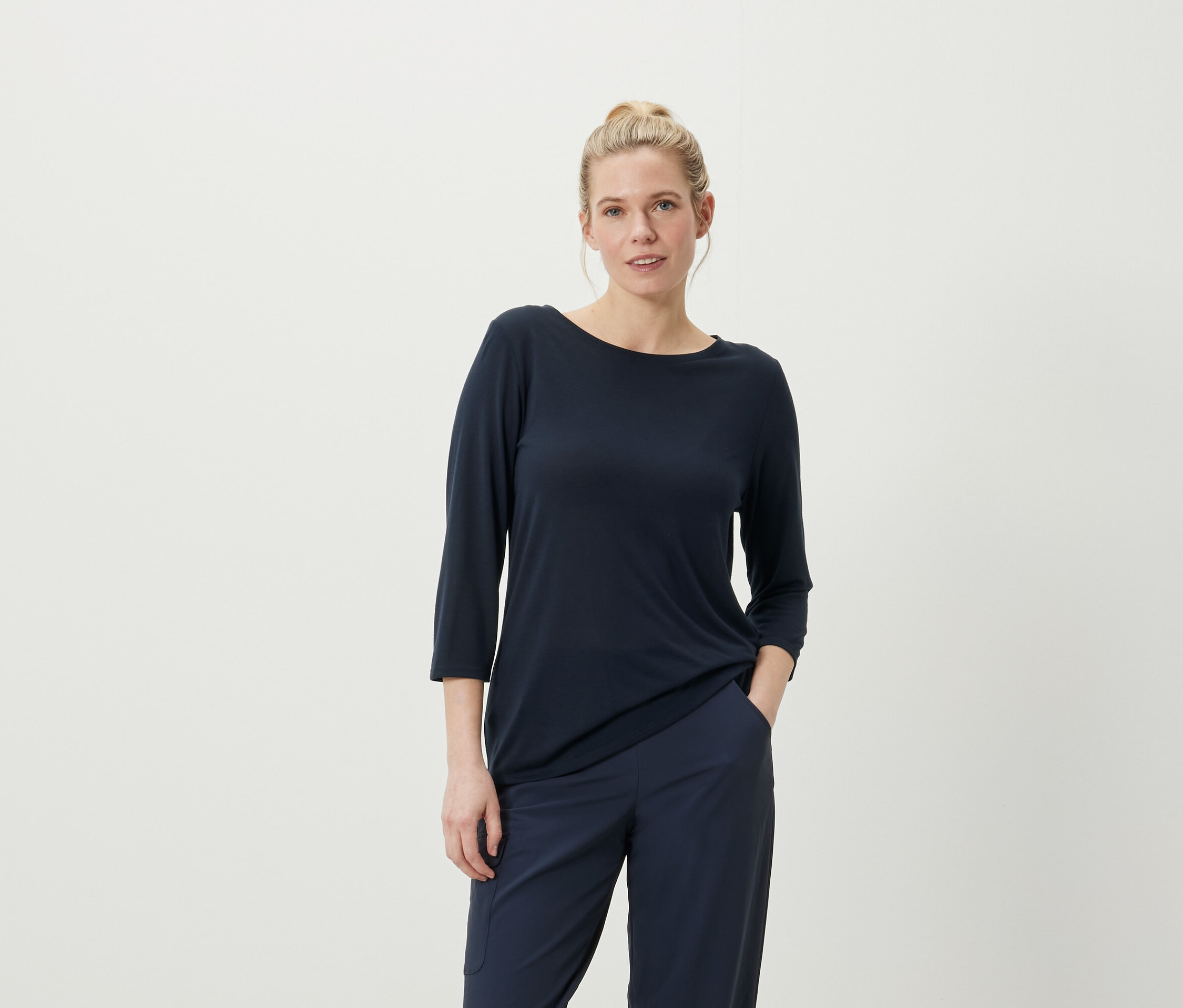 Frau posiert in marineblauem Dreiviertelarm-Shirt und Hose.