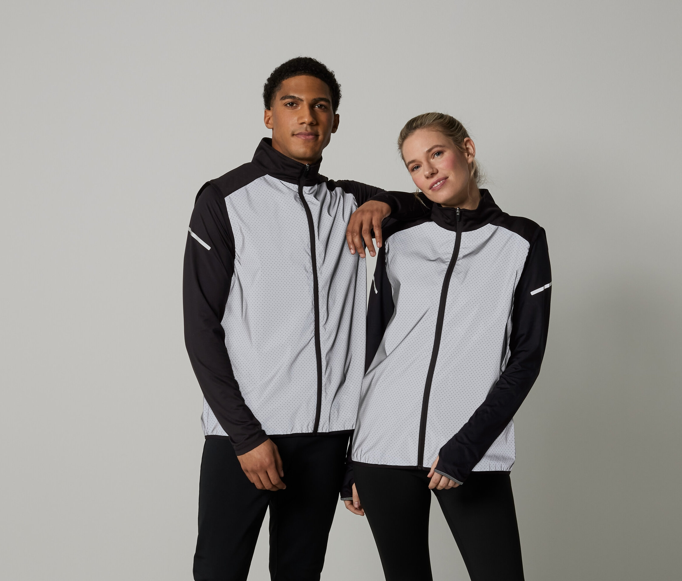 Mann und Frau posieren in langärmligen Jacken mit Reißverschluss.