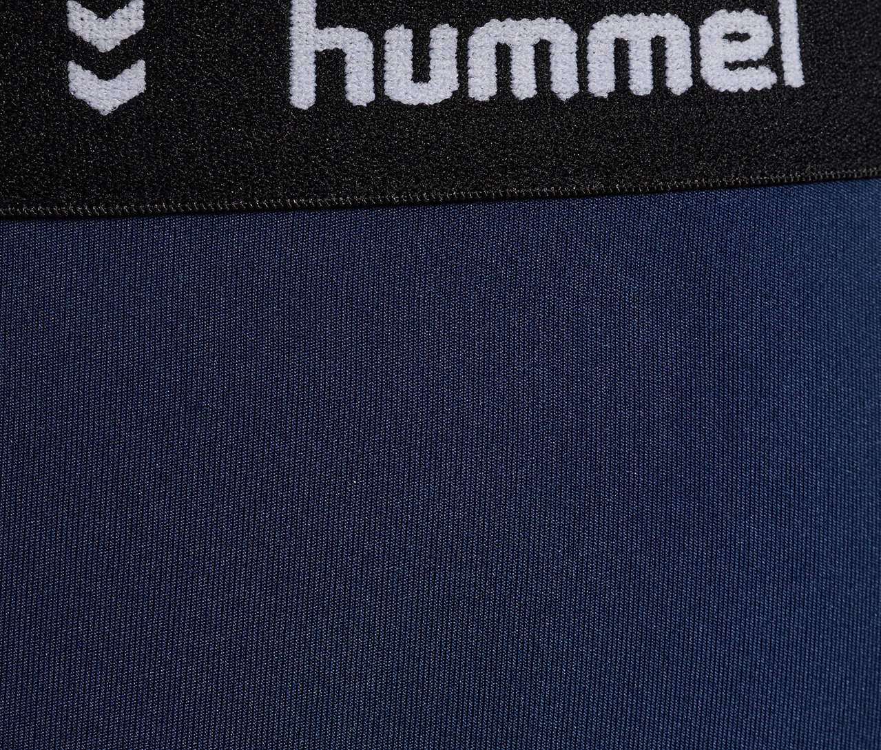 Detailaufnahme der blauen HUMMEL HMLJR Pulse Mid Waist Tight mit schwarzem Bund und Logo.