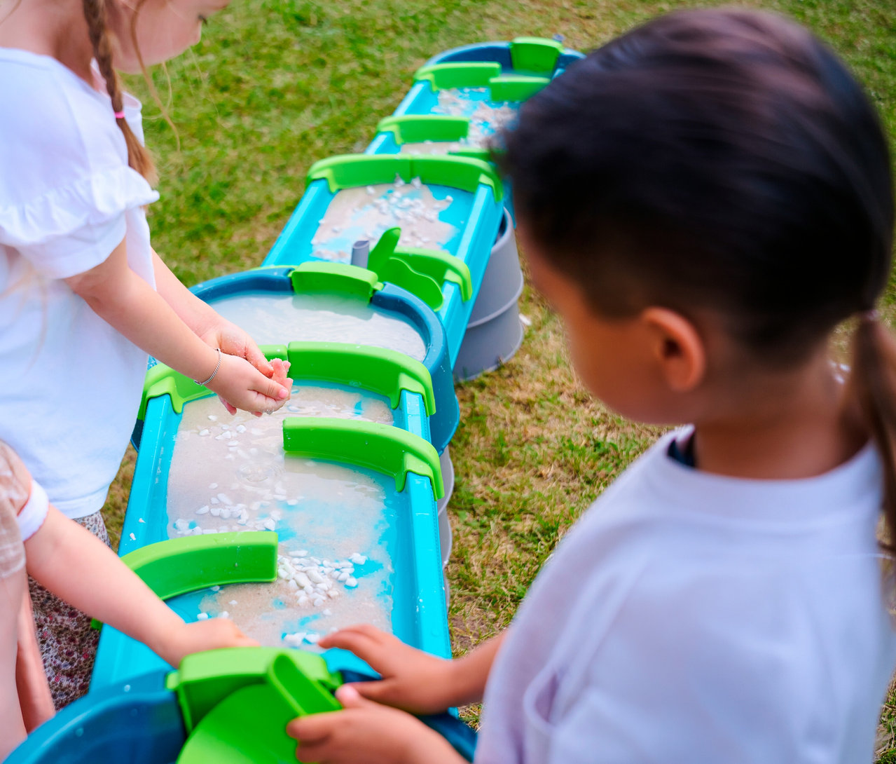 Kinder spielen mit der AquaPlay »Mudway STREAM« Matschbahn, die mit Wasser und Spielzeug gefüllt ist.