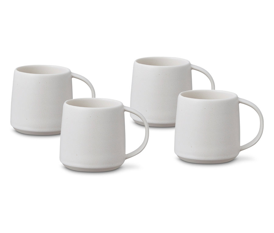 Vier weiße Keramiktassen mit Henkeln stehen auf einer weißen Oberfläche.