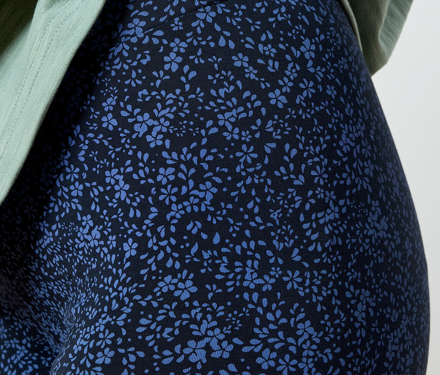 Detailansicht einer Person, die Leggings mit blauem Blumenmuster und ein hellgrünes Oberteil trägt.